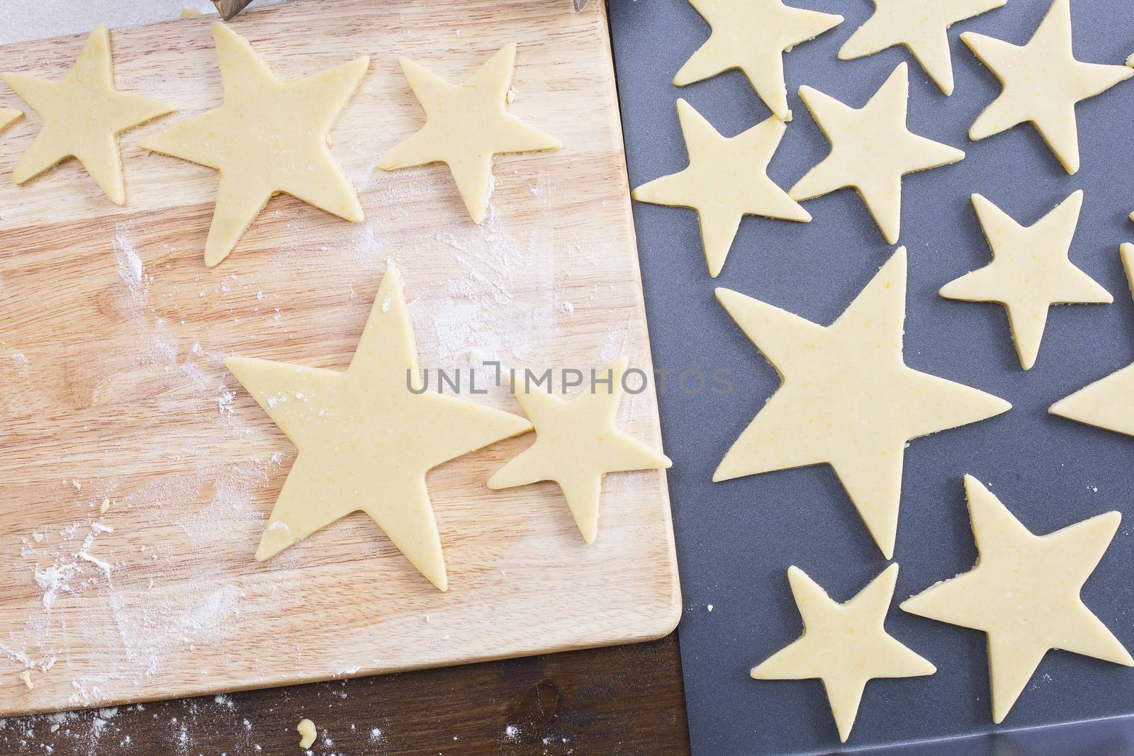 Star shaped Christmas cookie dough on cutting board and baking sheet, from above.