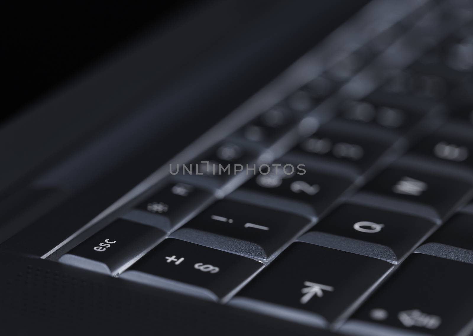 Closeup of backlit computer laptop keyboard selective focus on e by keneaster