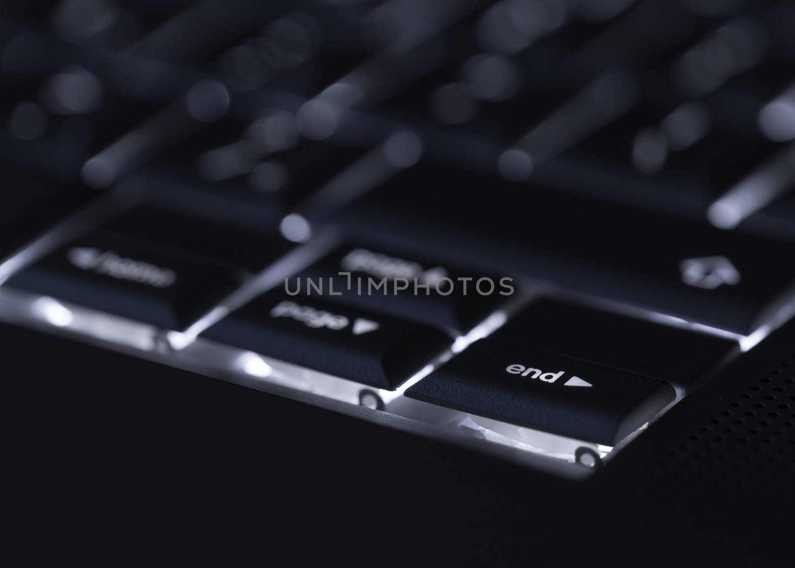 Closeup of backlit computer laptop keyboard selective focus on end key ideal for technology night hacker standout