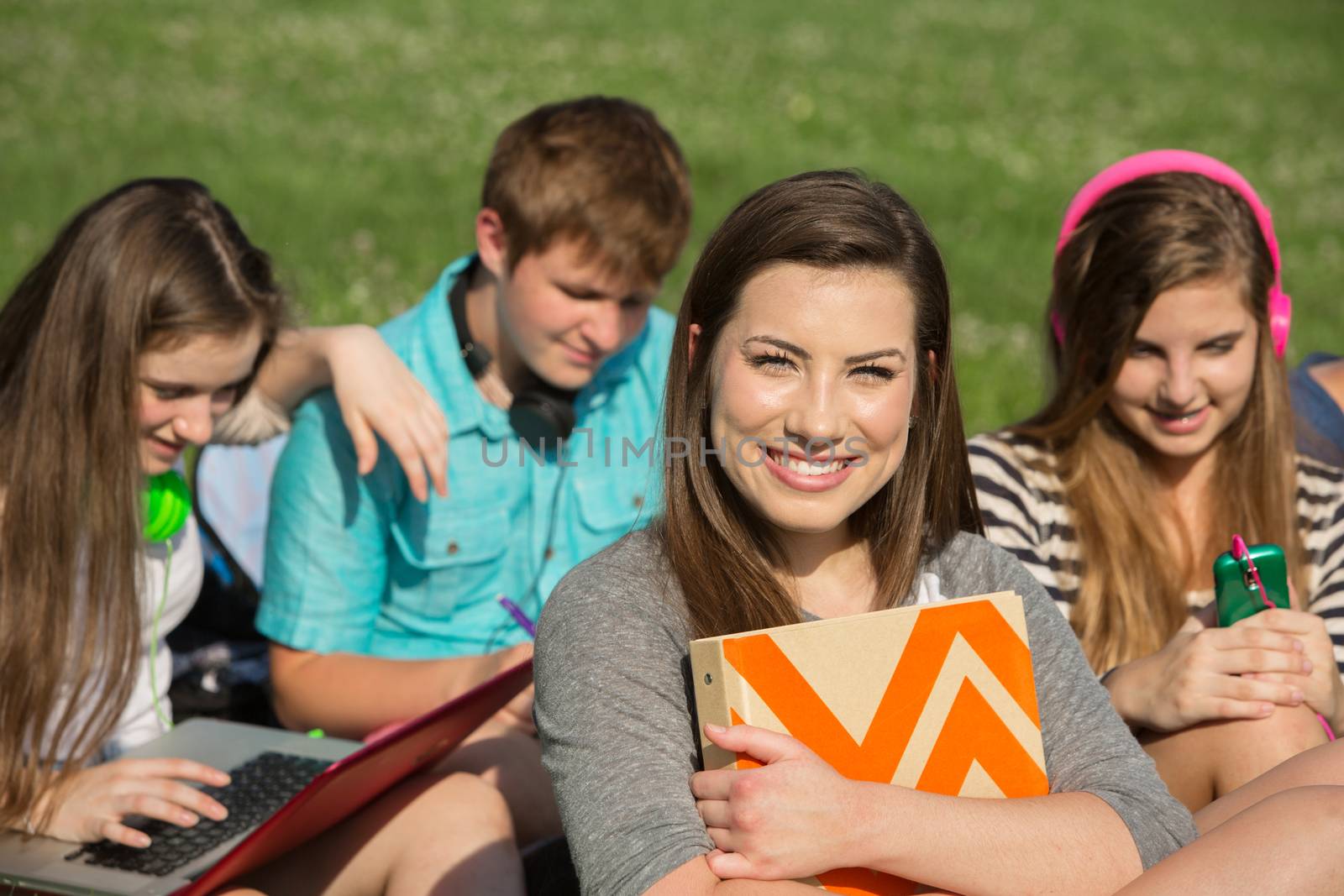 Cute teen girl holding binder with friends
