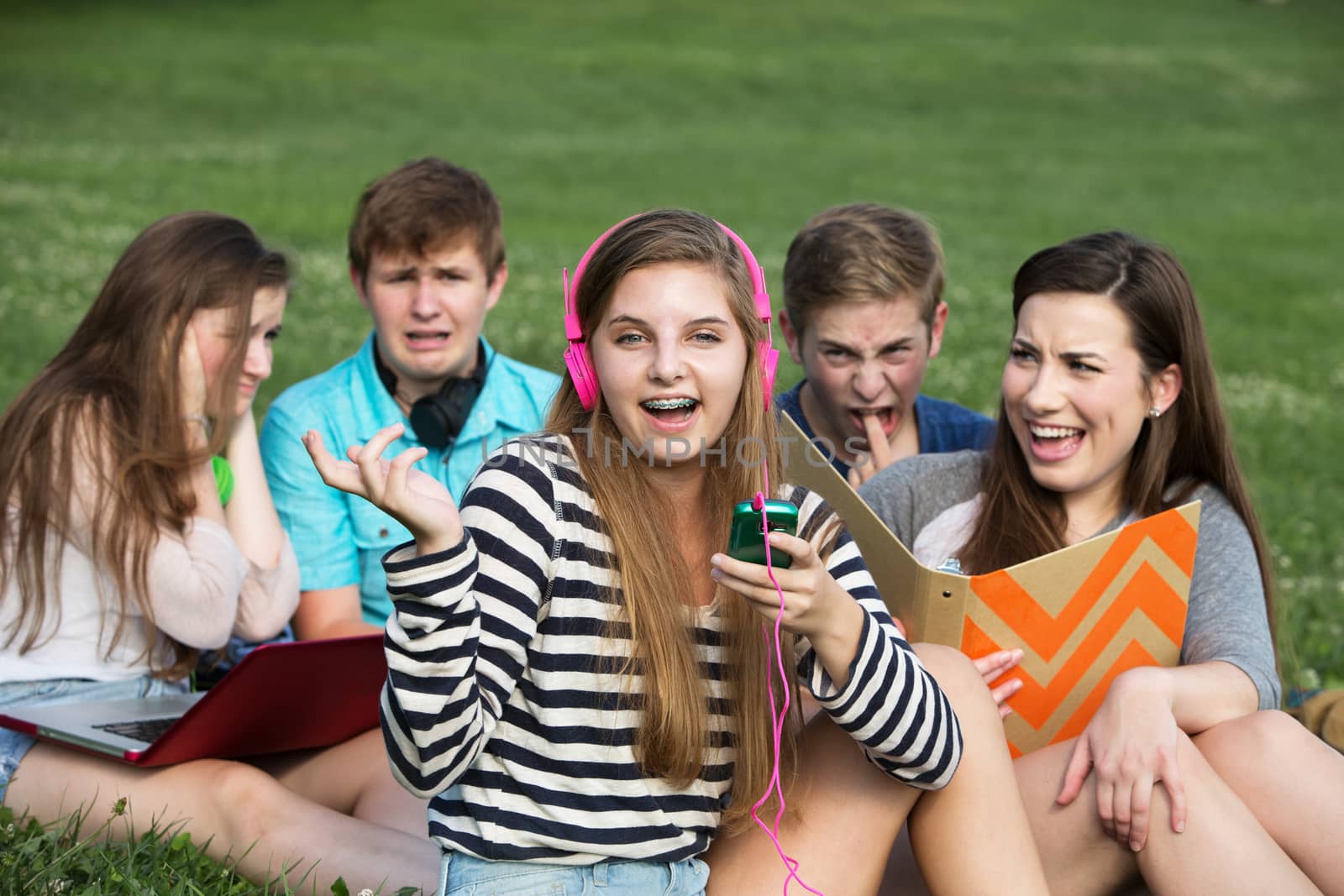 Singing teenage girl annoying friends studying outdoors