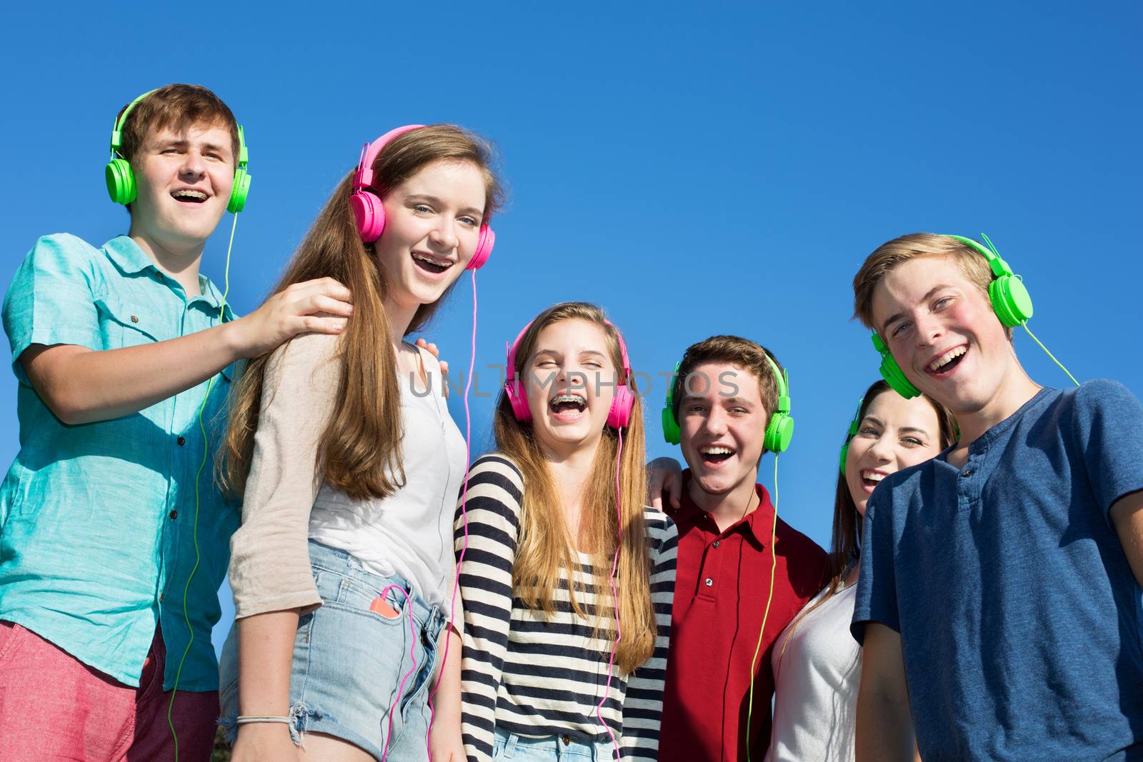 Group of six happy teenagers laughing outdoors
