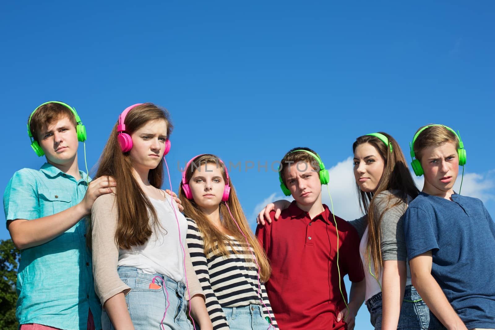 Group of frowning European teenagers with headphones