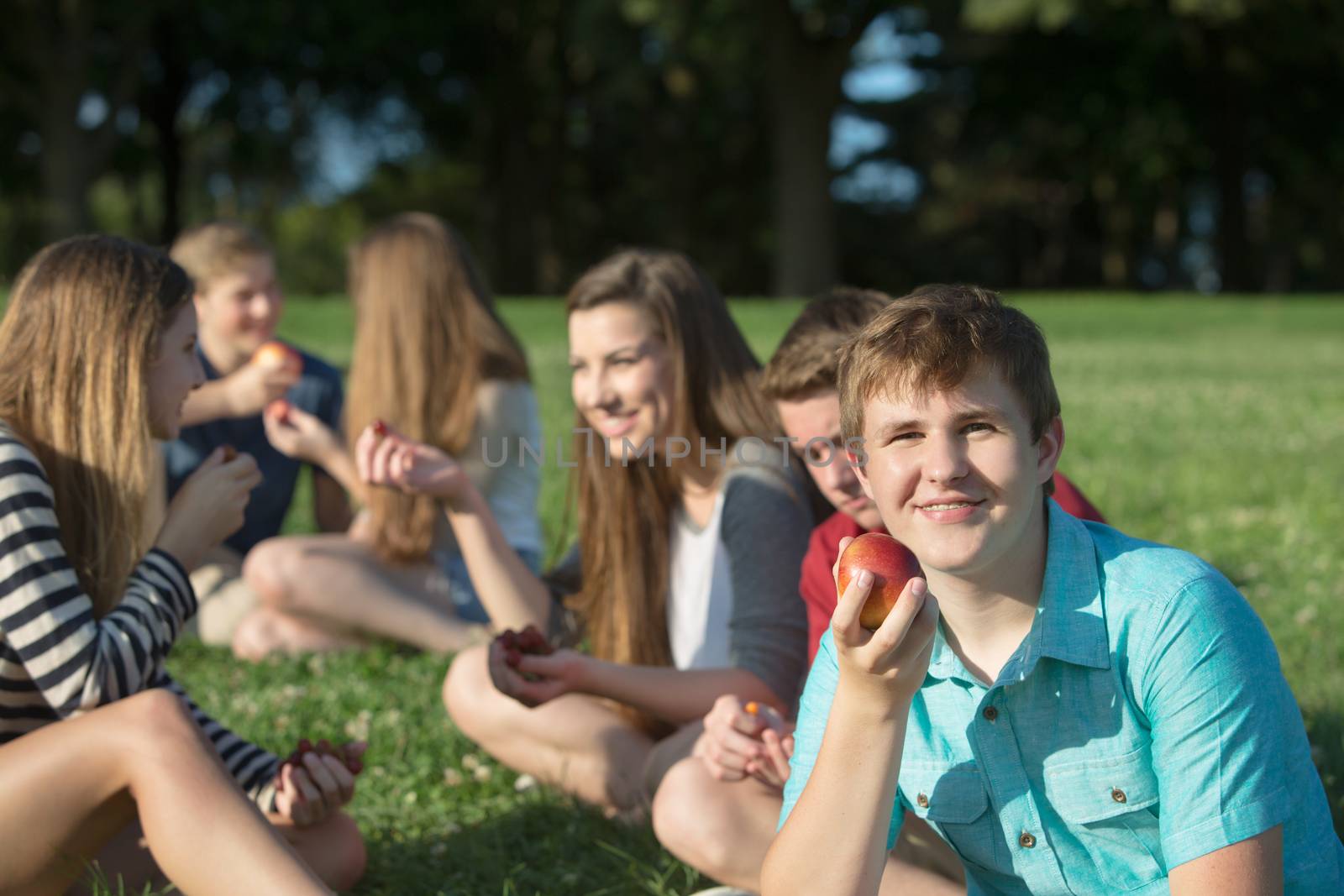Happy group of teenagers eating healthy snacks outdoors