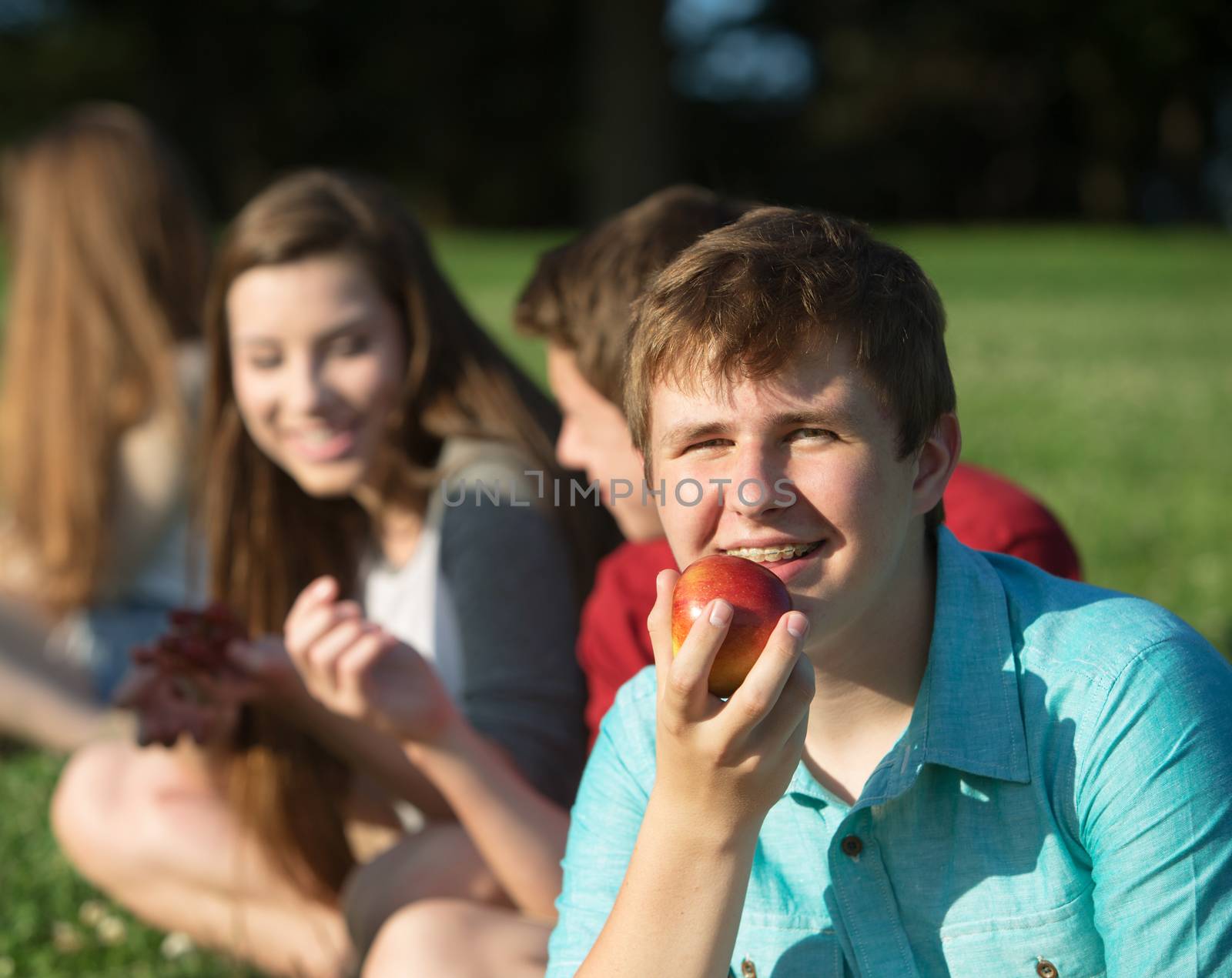 Happy young person with friends holding fruit