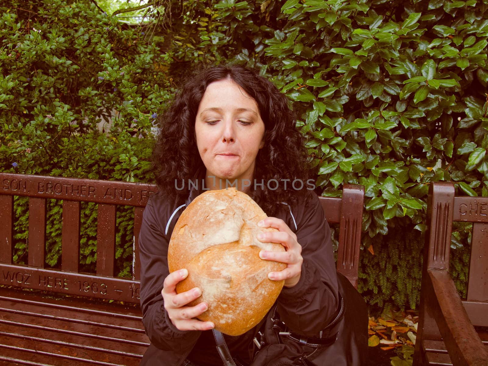 A portrait of hungry pretty young brunette eating huge bread