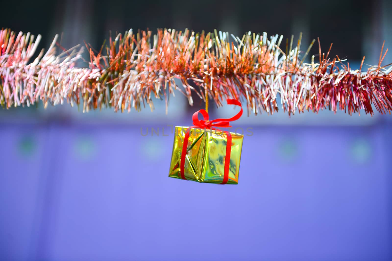 Closeup golden gift box, christmas ornament hanging on tree