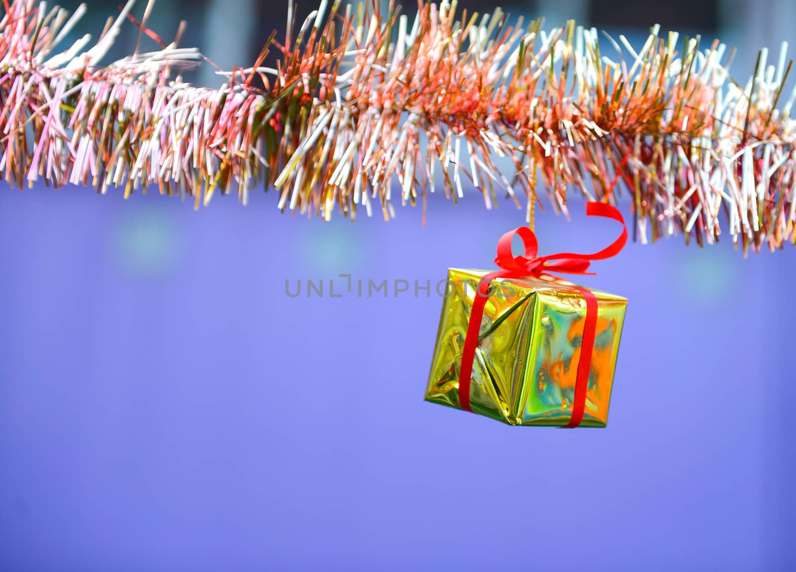 Closeup golden gift box, christmas ornament hanging on tree 