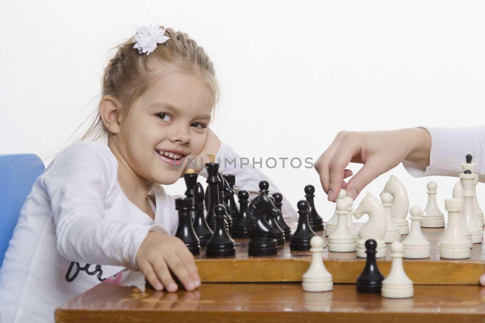  Four-year-old girl playing in chess. Girl fun looking at the Board,preparing to make the next move