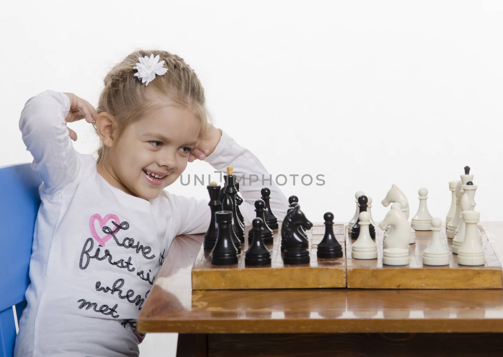  Four-year-old girl playing in chess. Girl fun looking at the Board,preparing to make the next move