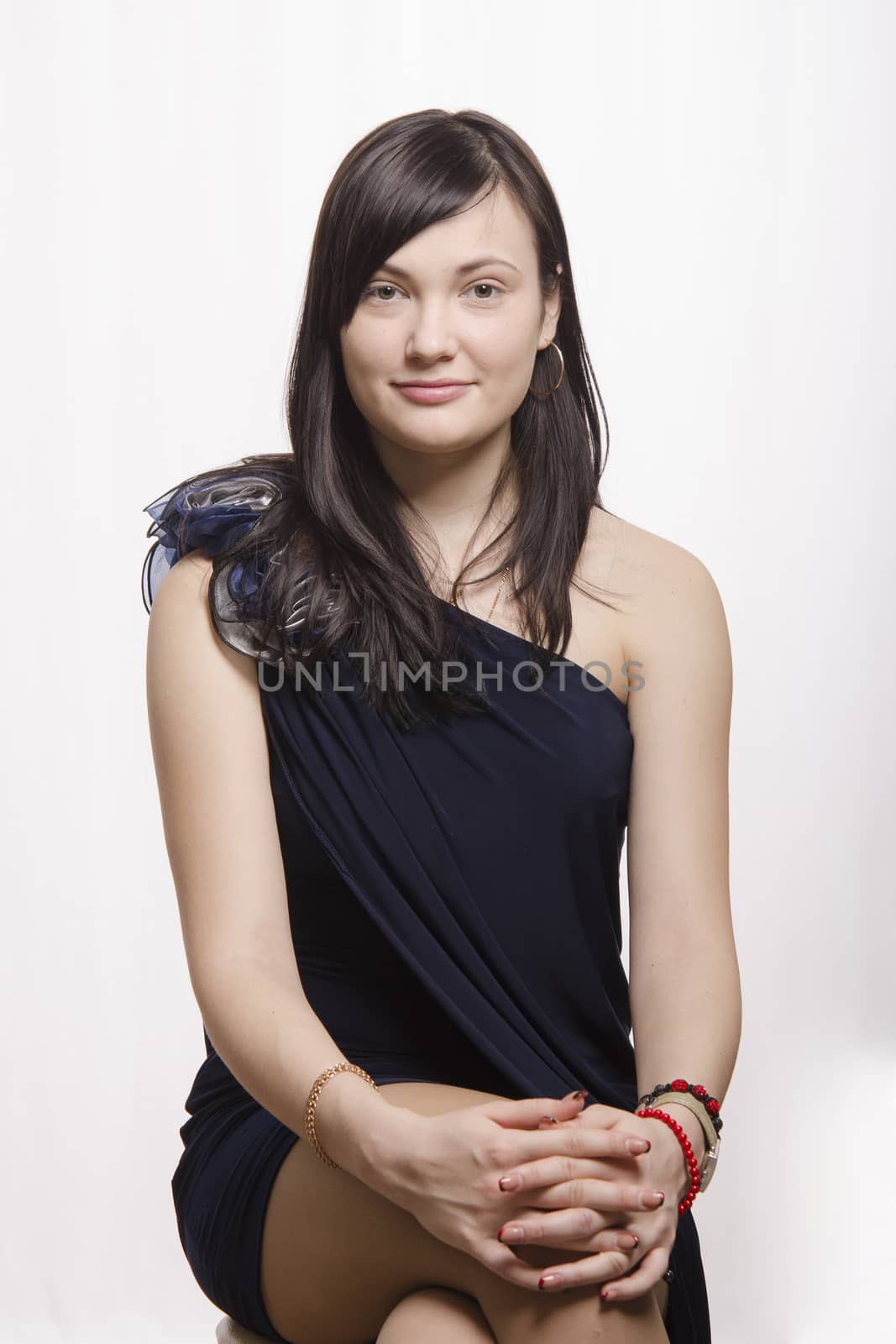 Portrait of a beautiful twenty-year-old girl, brunette. Girl sits on the chair and smiling looks in the frame