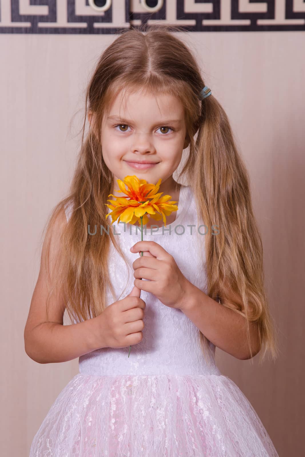 Five-year girl in a white dress holding a flower