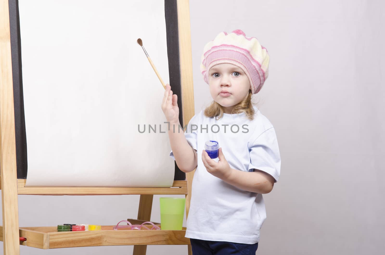 Three-year-old girl playing in the artist. Girl draws on the easel paints