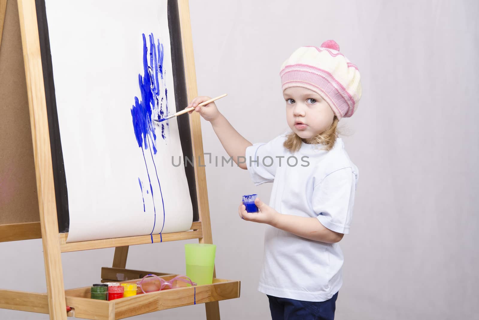 Three-year-old girl playing in the artist. Girl draws on the easel paints