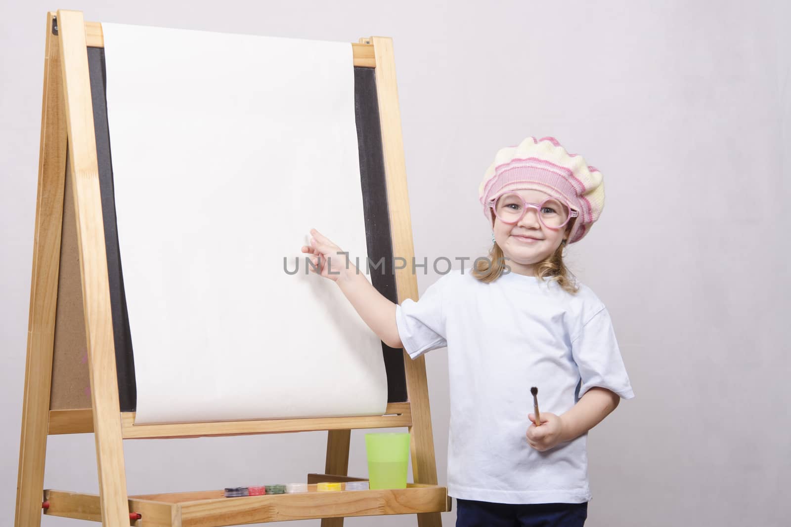 Three-year-old girl playing in the artist. Girl draws on the easel paints