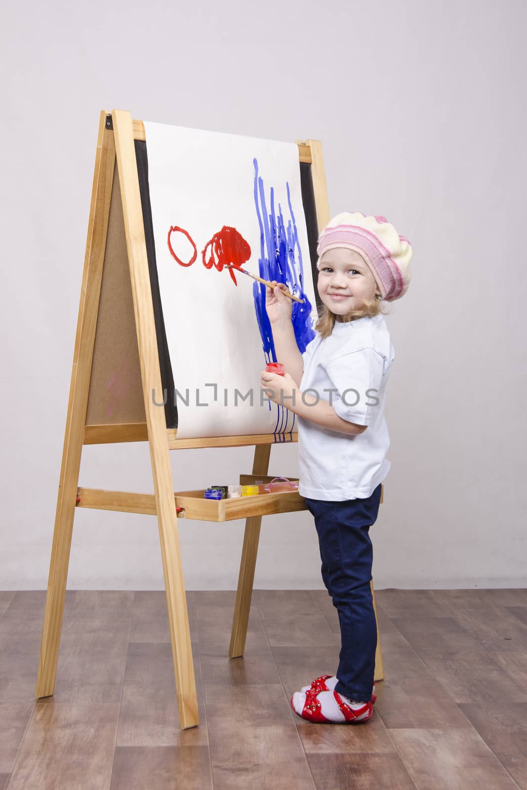 Three-year-old girl playing in the artist. Girl draws on the easel paints