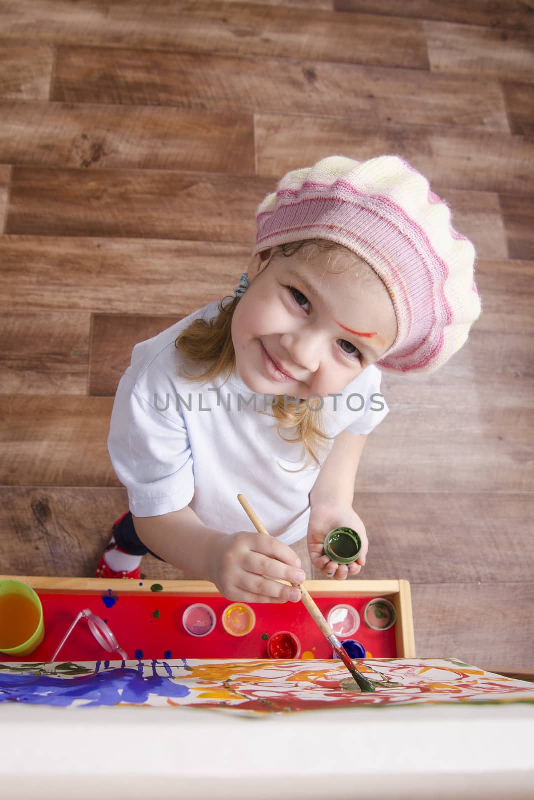 Three-year-old girl playing in the artist. Girl draws on the easel paints