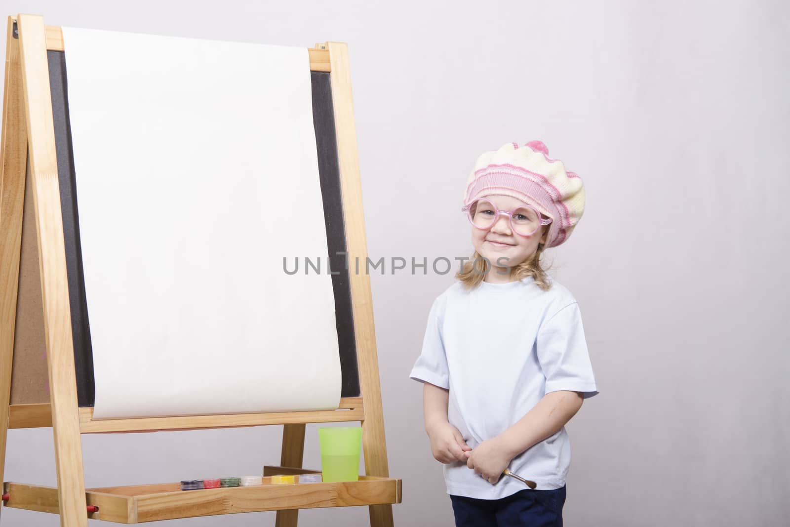 Three-year-old girl playing in the artist. Girl draws on the easel paints