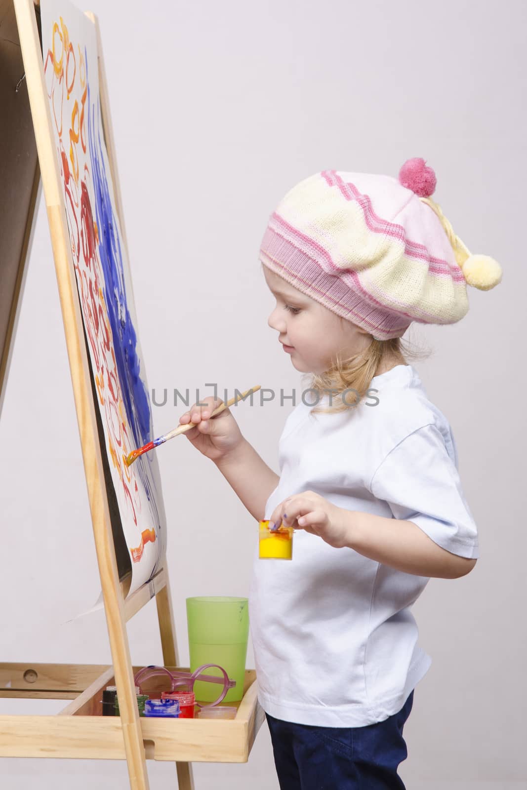 Three-year-old girl playing in the artist. Girl draws on the easel paints