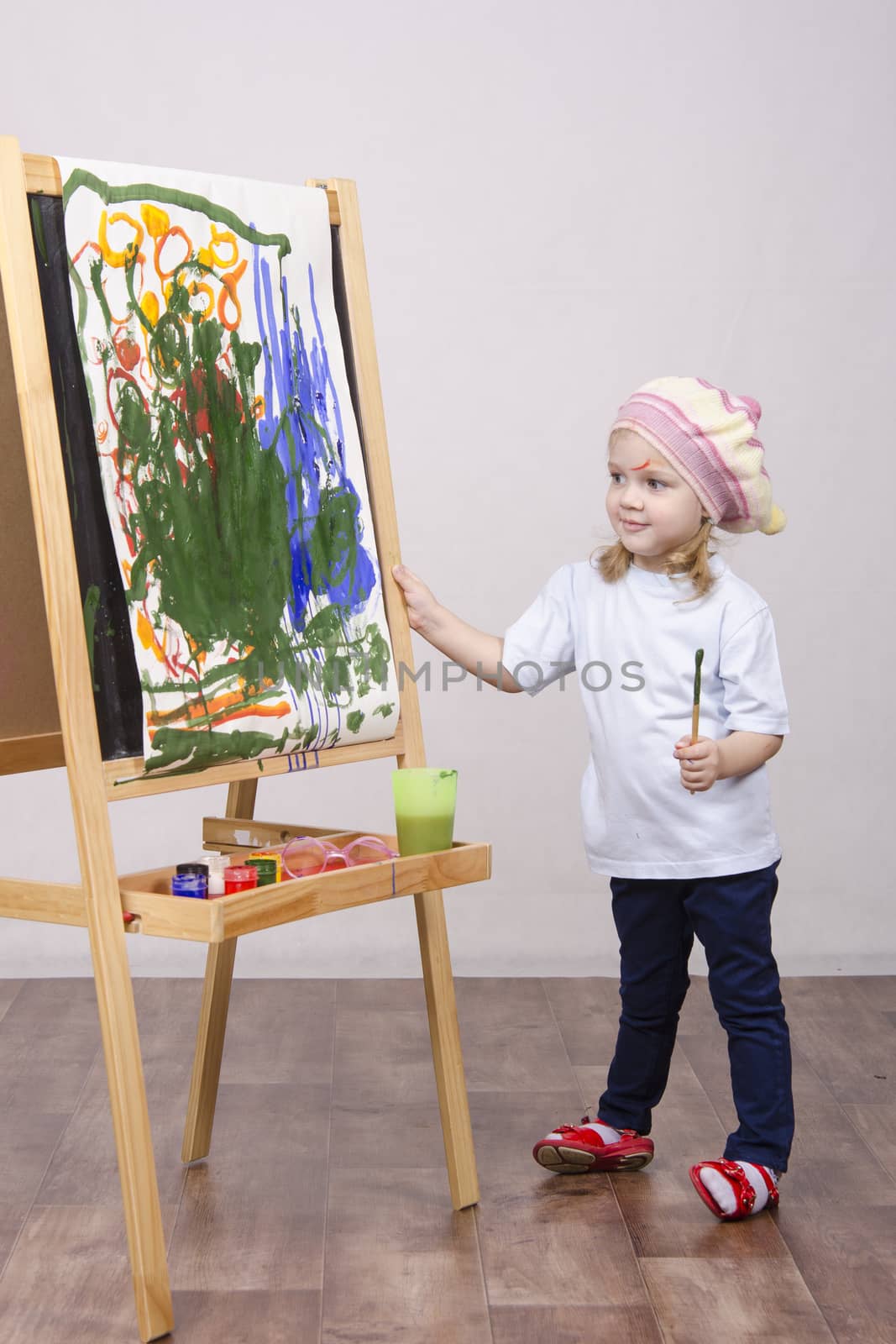 Three-year-old girl playing in the artist. Girl draws on the easel paints