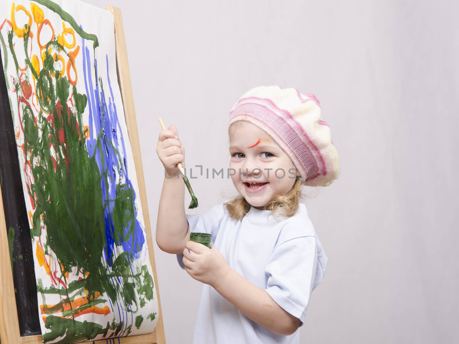 Three-year-old girl playing in the artist. Girl draws on the easel paints