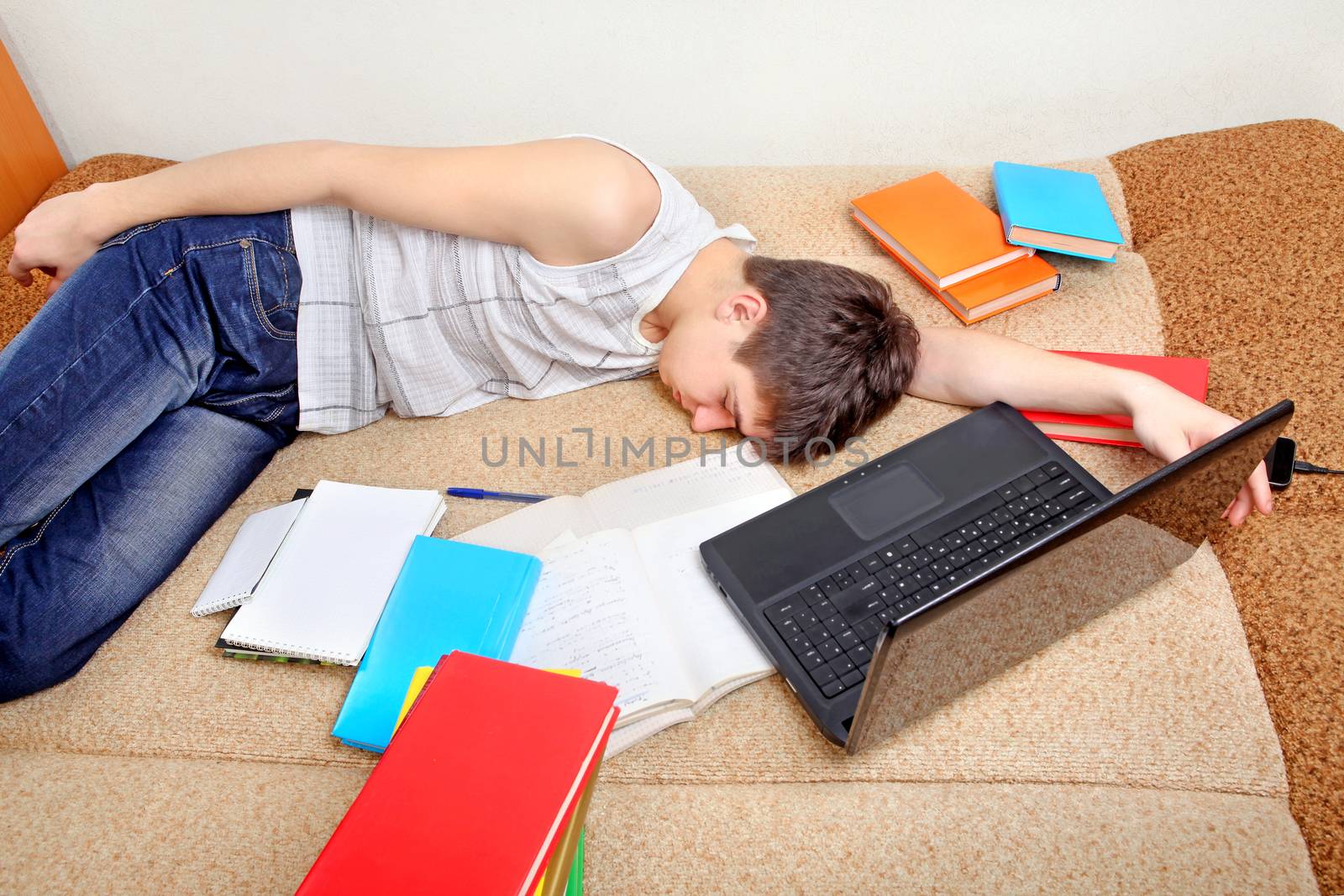 Tired Teenager sleeping on the Sofa with the Books