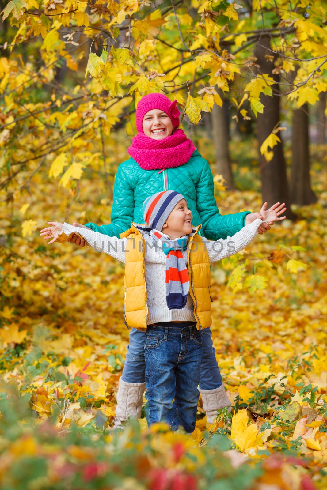 Portrait of Adorable cute boy and girl with autumn leaves in the beautiful park
