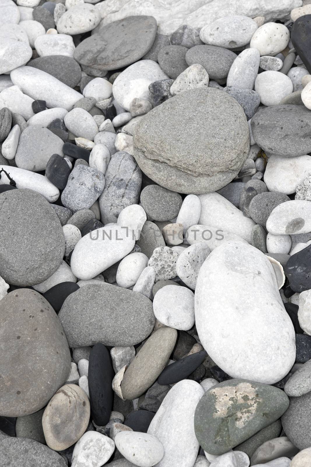 grey pebbles and rocks in a beach by morrbyte