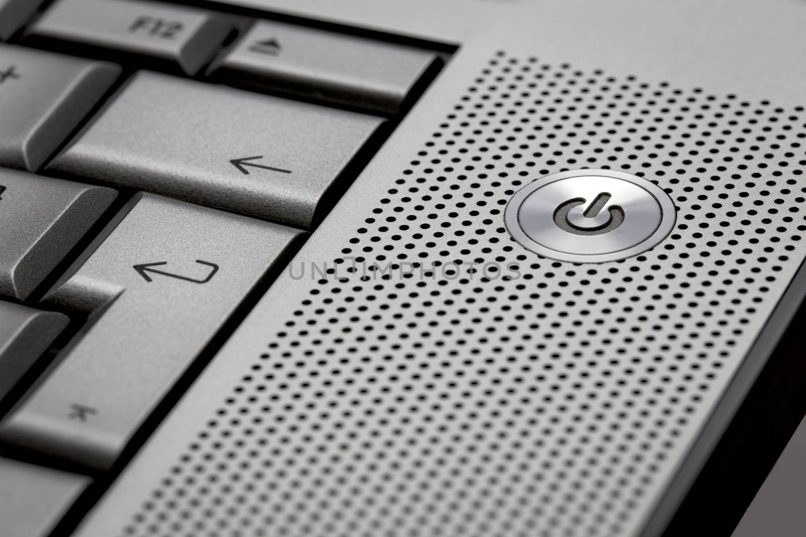 Closeup of silver computer laptop selective focus on standby on button ideal for technology business start power energy symbol
