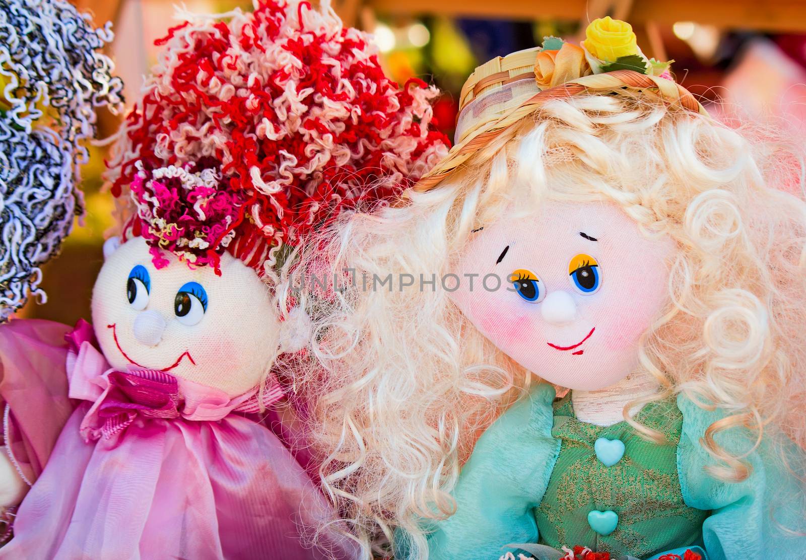 The souvenirs in the form of amusing dolls sewed from rags of fabric and laces. Are presented on a beautiful background with an embroidery.