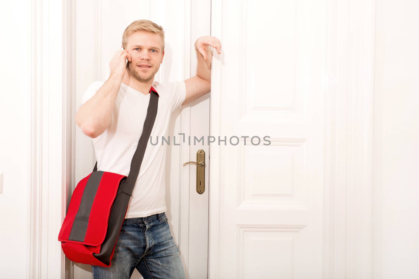 A young and busy student coming home while talking on the smartphone.