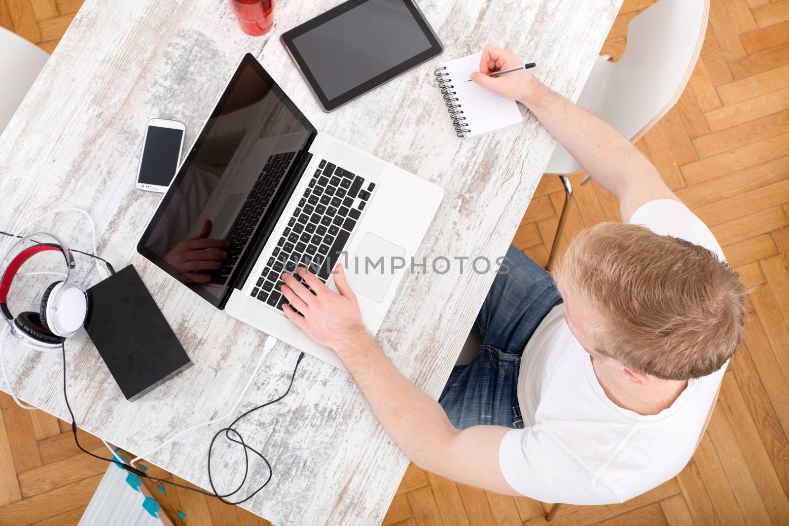 A young caucasian man working in his home office seen from above.
