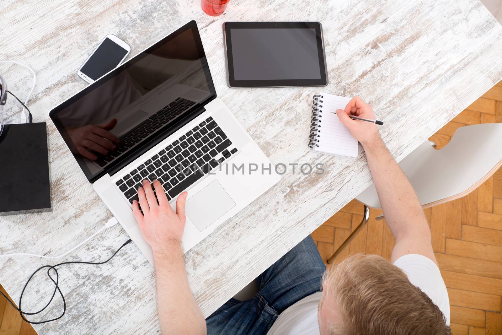 A young caucasian man working in his home office seen from above.
