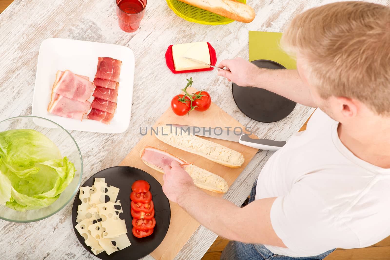 A young man preparing a sandwich in the kitchen.
