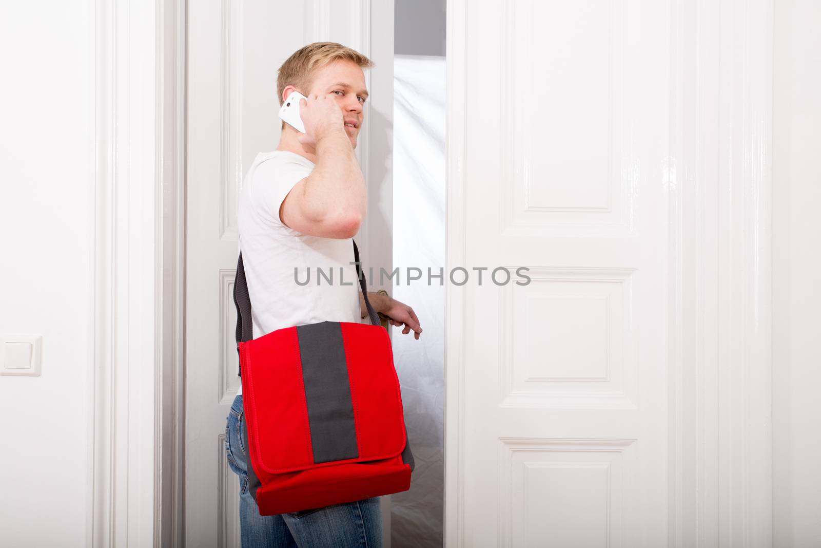 A young and busy student coming home while talking on the smartphone.