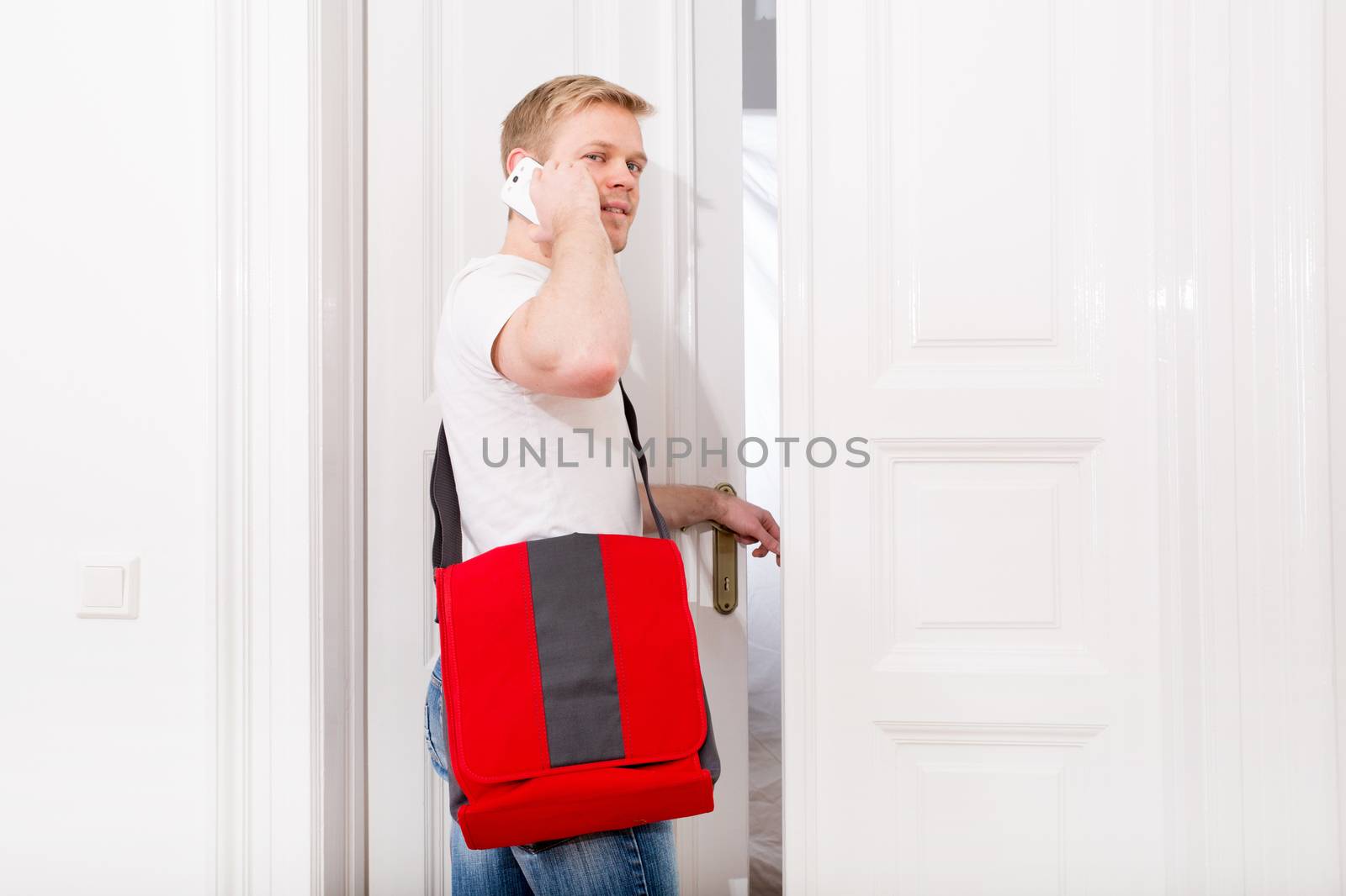 A young and busy student coming home while talking on the smartphone.