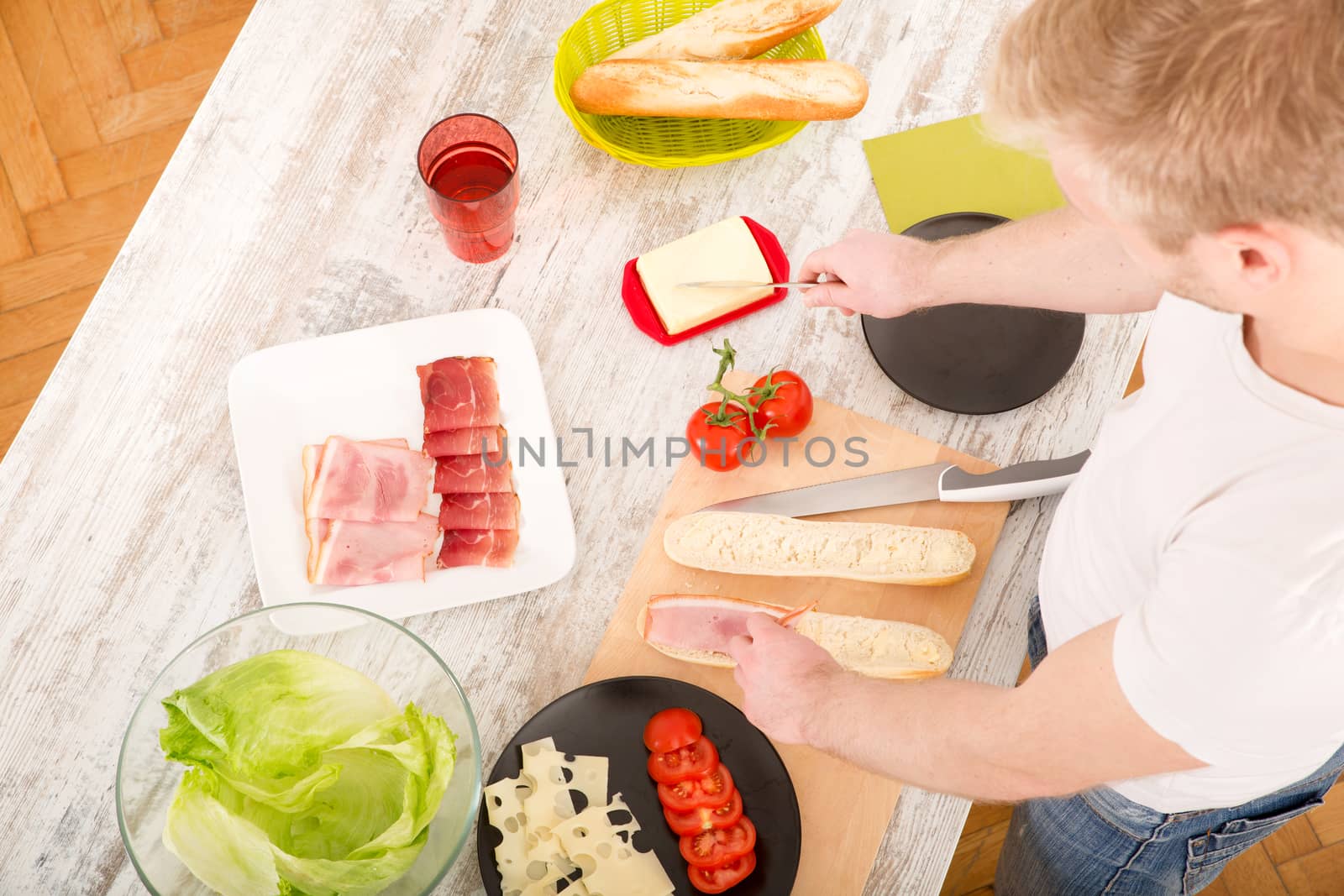 A young man preparing a sandwich in the kitchen.
