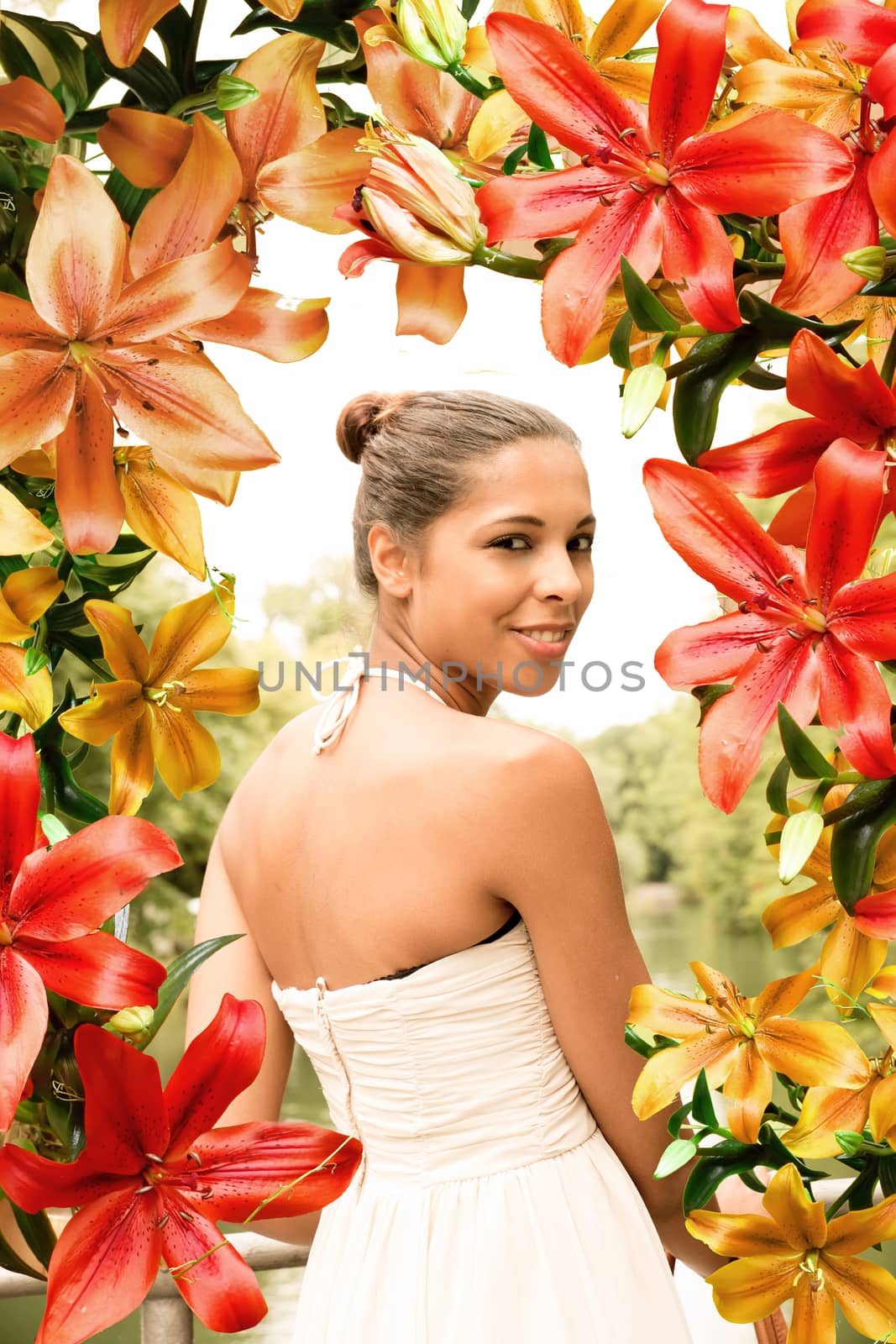 A young woman in a white dress surrounded by flowers.