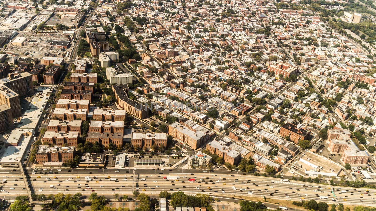 Aerial view of the Borough of Queens, New York, showing densely packed buildings and a multi-lane super highway