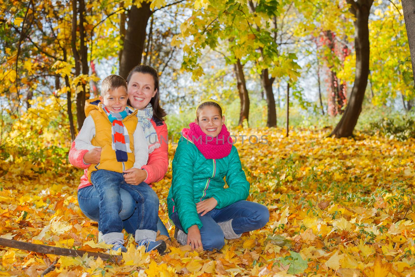 Happy mother with her kids relaxing in autumn park