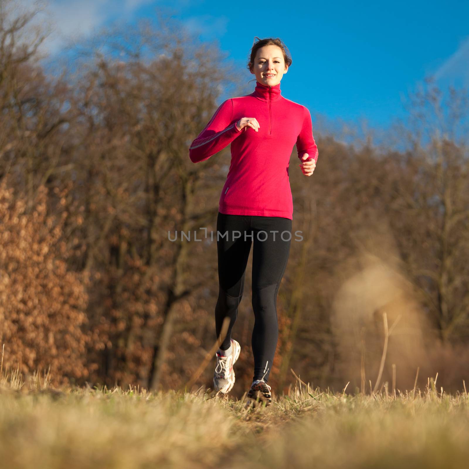 Young woman running outdoors on a lovely sunny winter/fall day