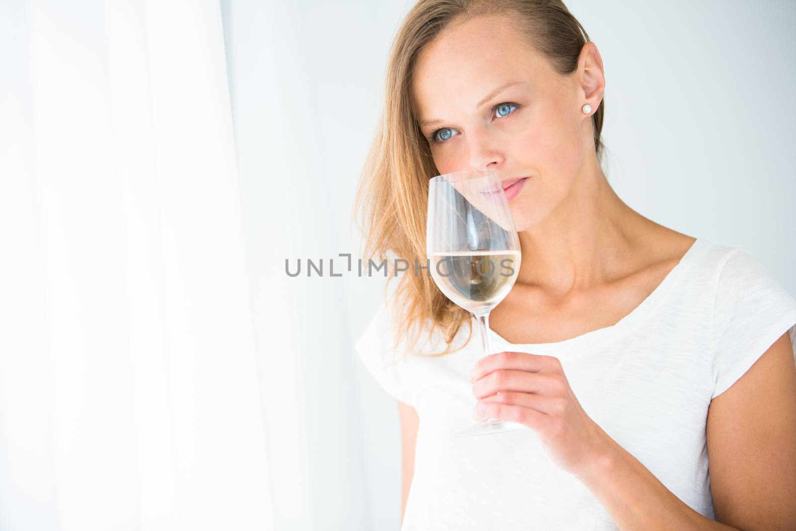Gorgeous young woman with a glass of wine, smelling the lovely drink, savouring every sip (shallow DOF; color toned image)