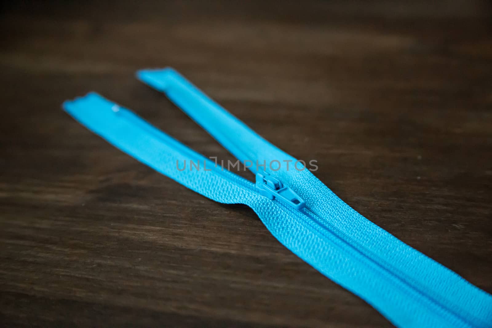 Blue clothing zipper on dark wood background