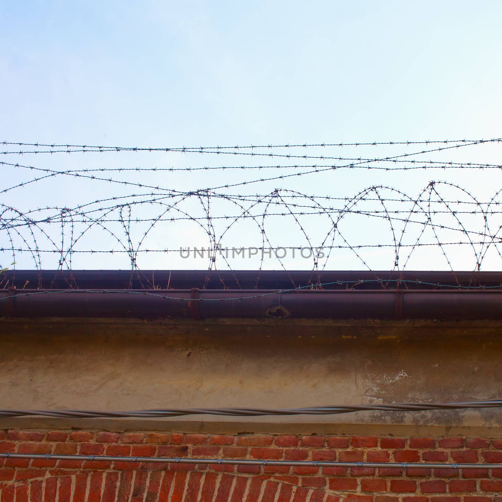 Barb wire on top of a wall, blue sky
