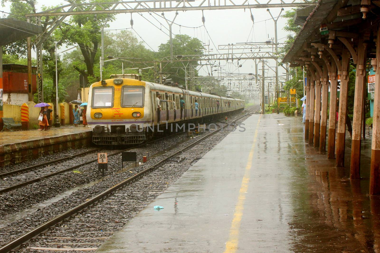 An Indian local train leaves a rural station during heavy monsoon rains season