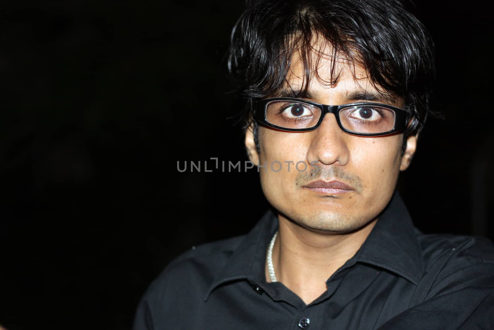 A portrait of an angry Indian man wearing glasses