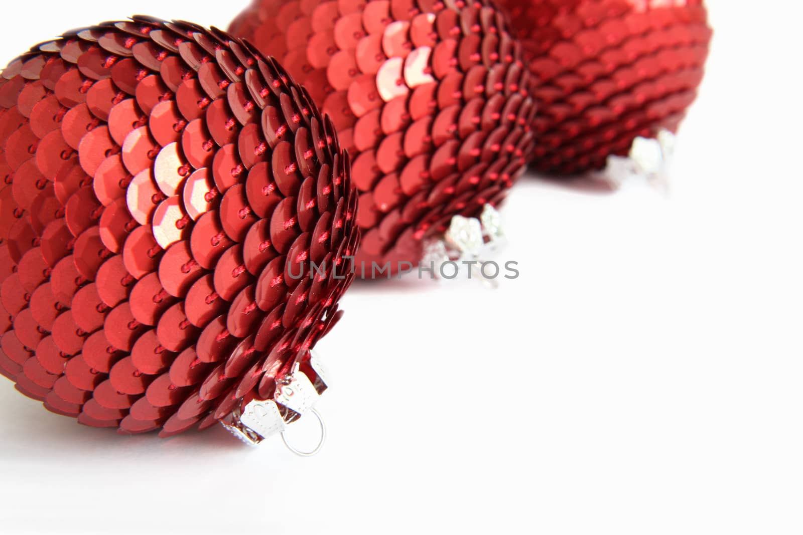 Three red Christmas sequin baubles on white.