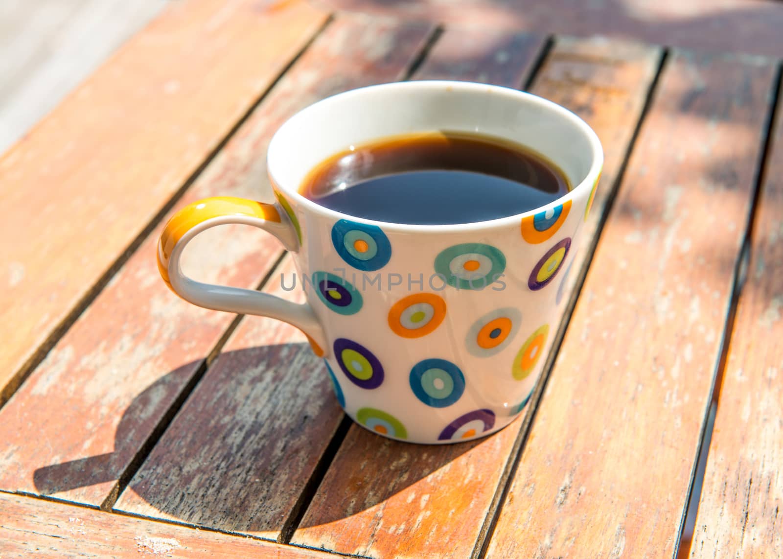 Colorful cup of coffee on wooden table 