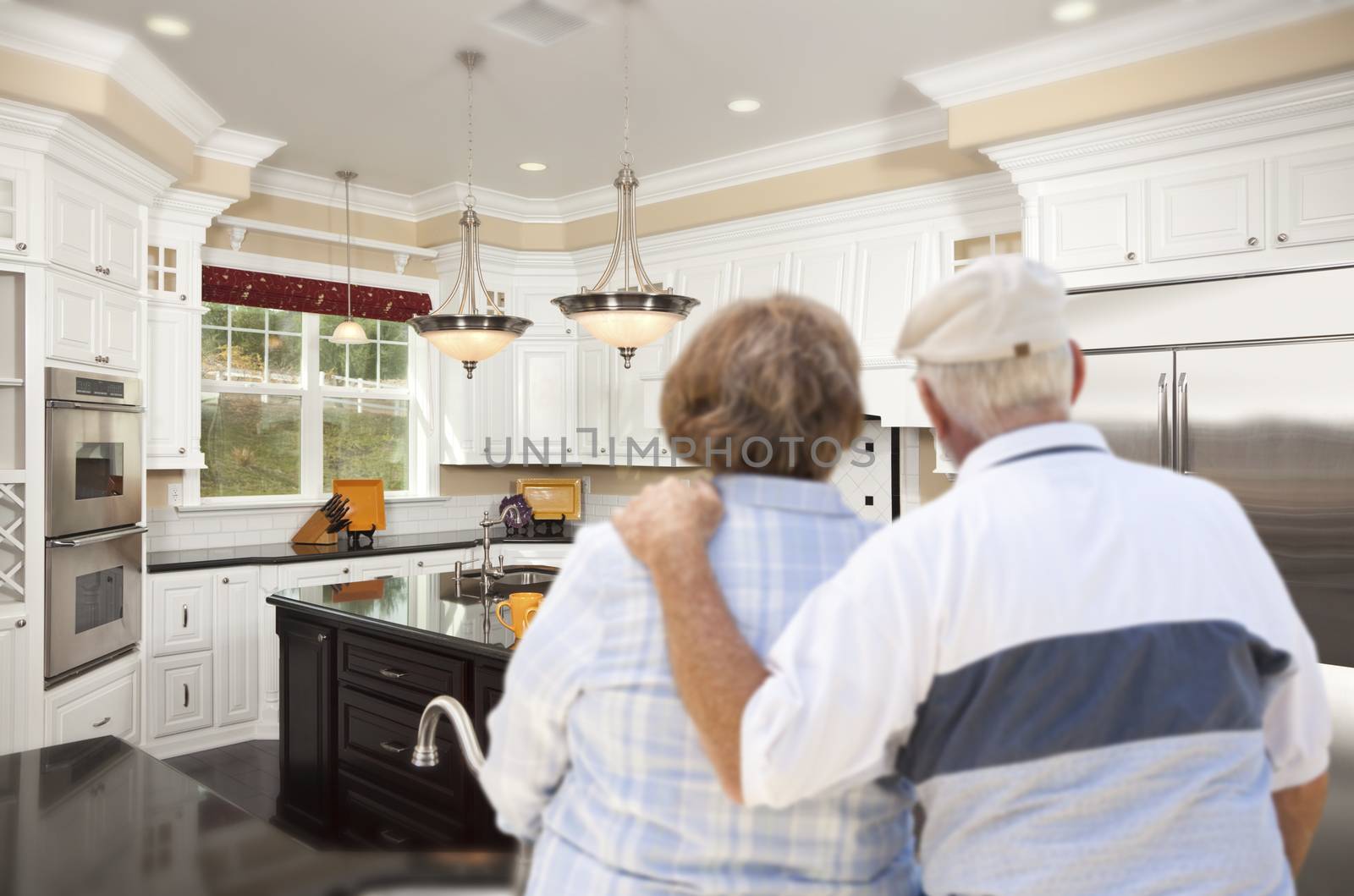 Happy Senior Couple Looking Over Beautiful Custom Kitchen Design.