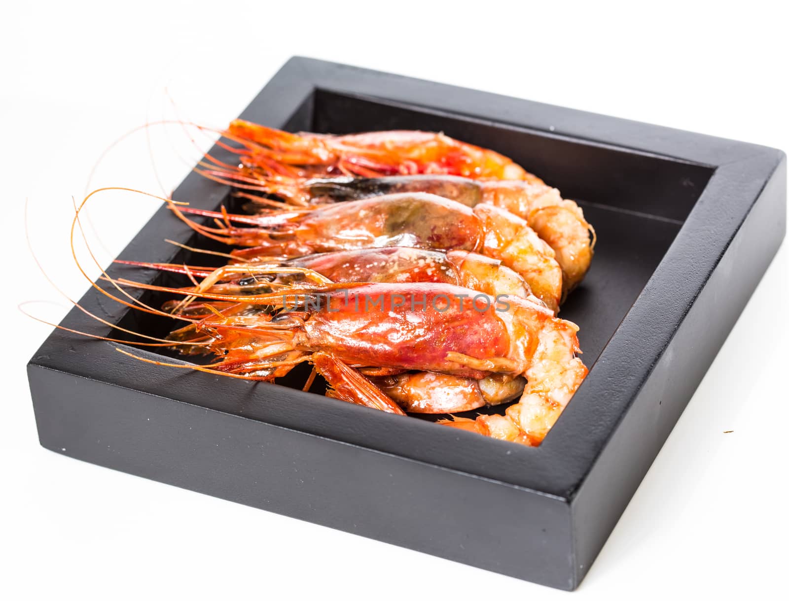 grilled shrimp in black plate on white background. by sarymsakov